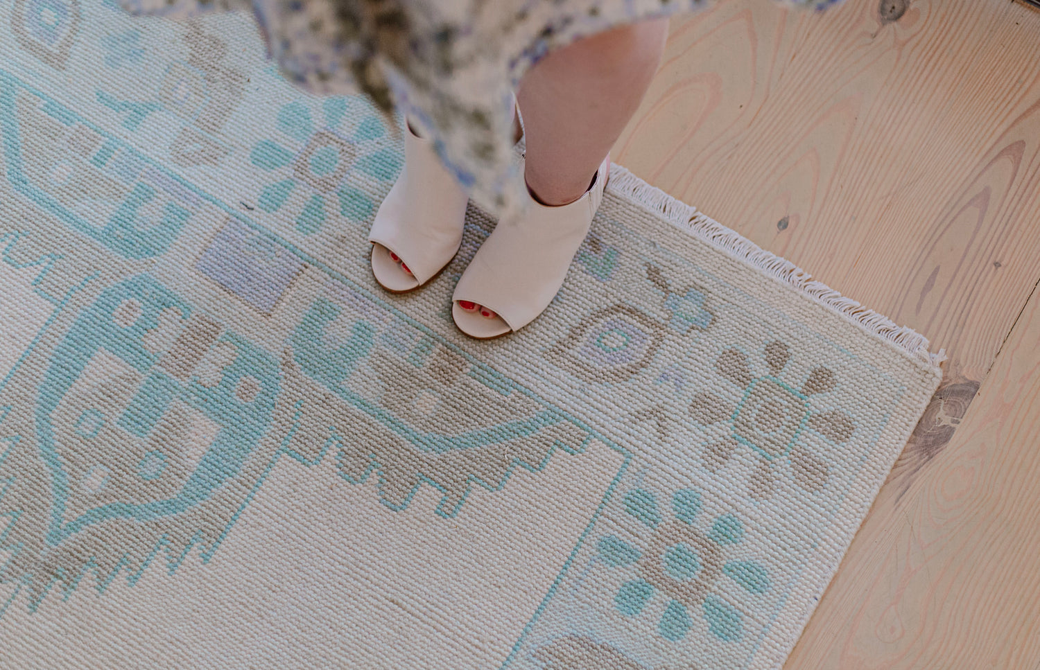 Lauren Egger Designs custom rug in browns, blues, and tans, with feet standing on it